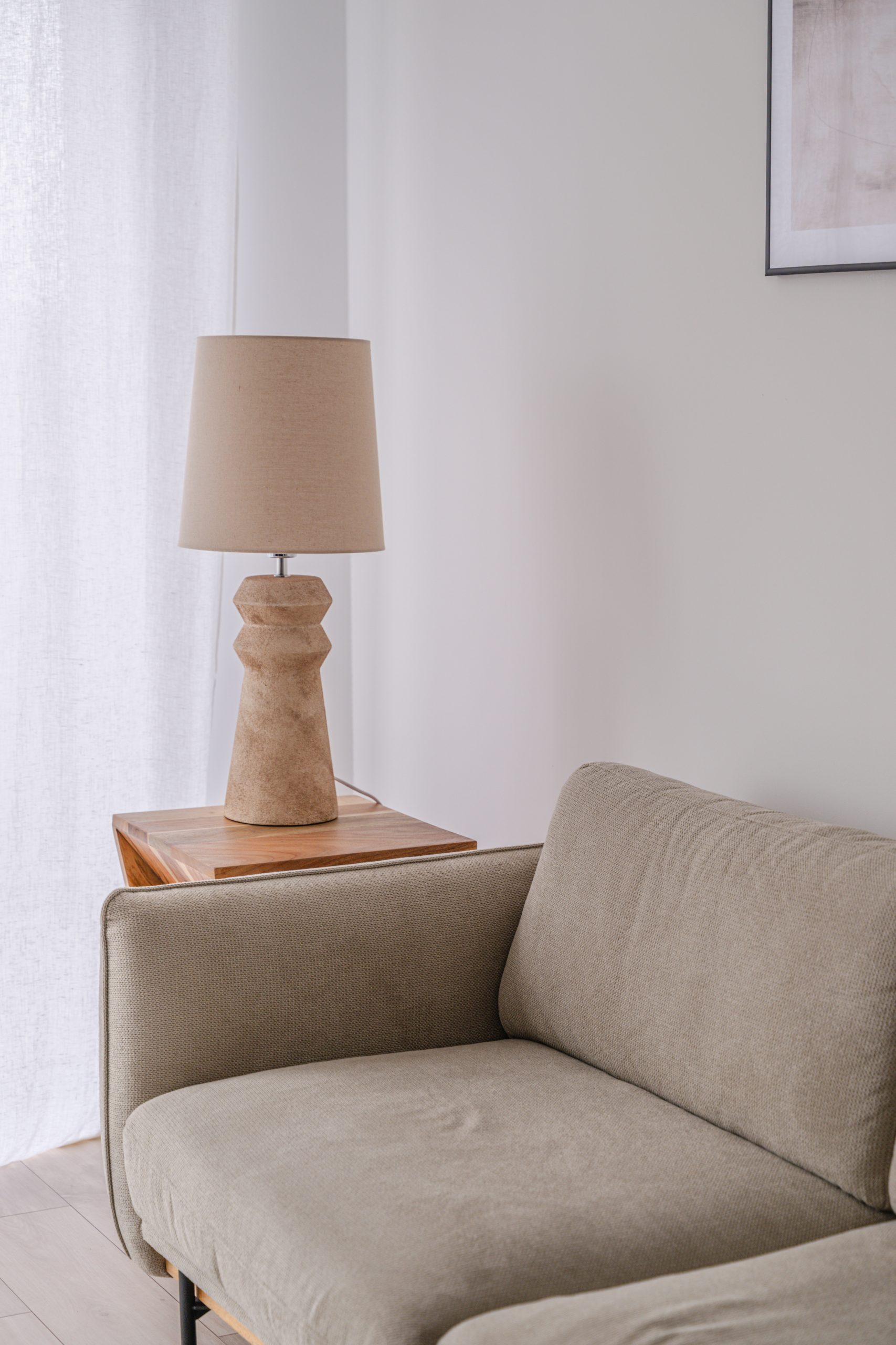 Lampe en bois posée sur une table d'appoint, canapé en lin beige - architecte d'intérieur sarthe
